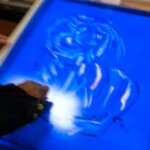 Mhiach subtracting the Akua ink before printing over one of his watercolor painted figures.