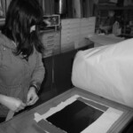 Lindsay Buchman surveys her plate as she places paper stencils along the plate's edges.